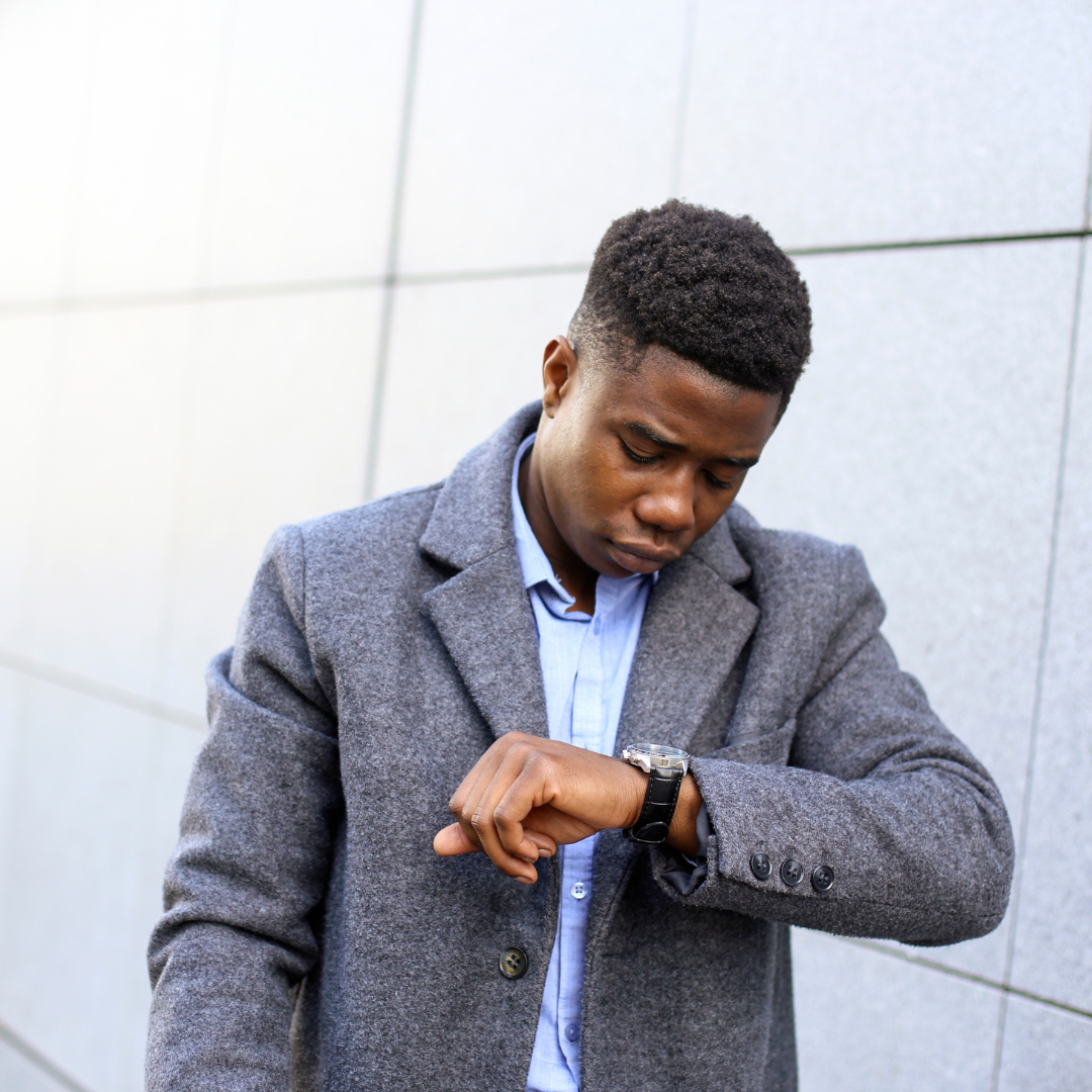 Man in gray coat looking at his watch, symbolizing leaving a networking event early.